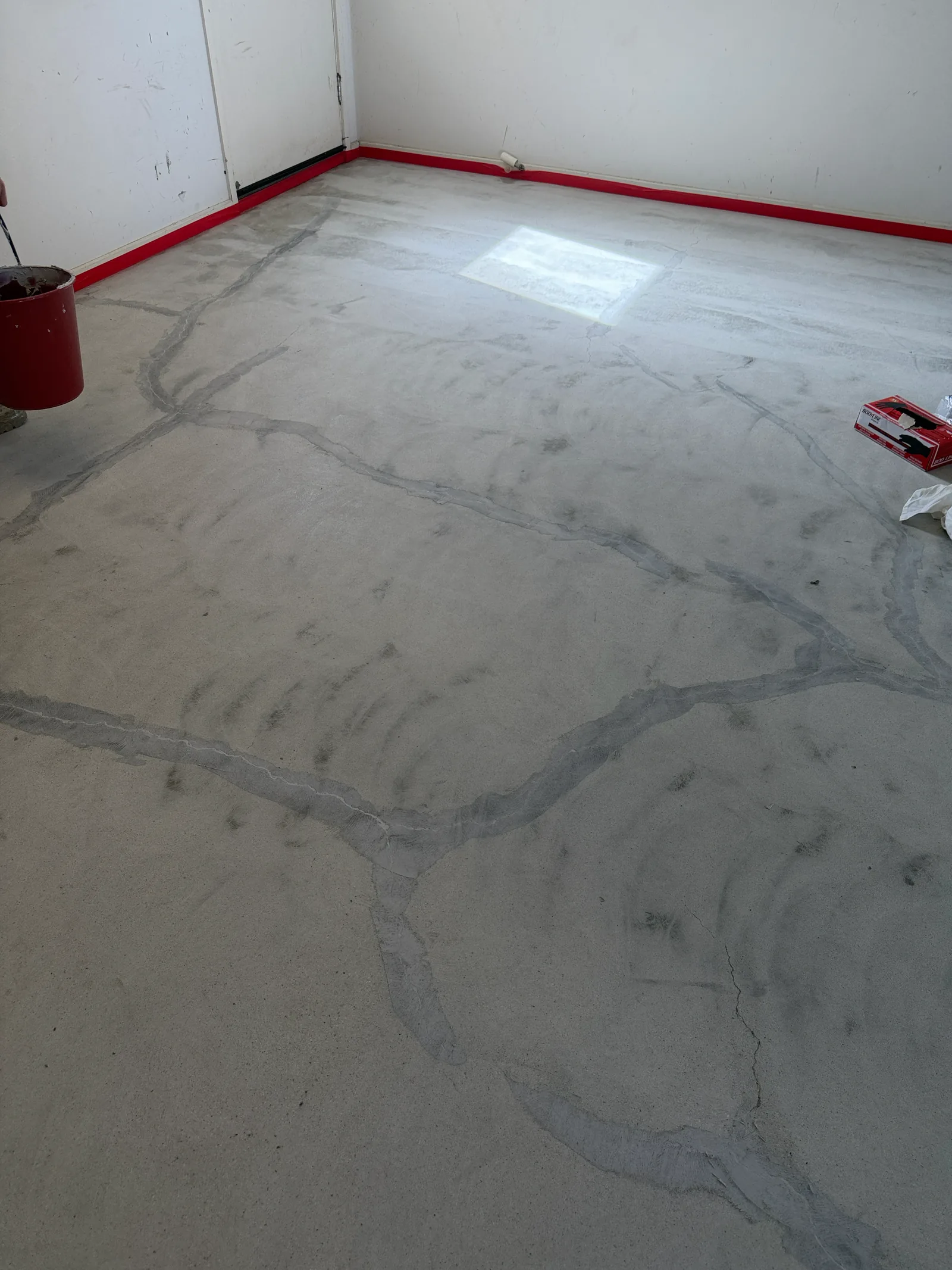 Concrete slab with surface cracks and red skirting before epoxy preparation, Perth